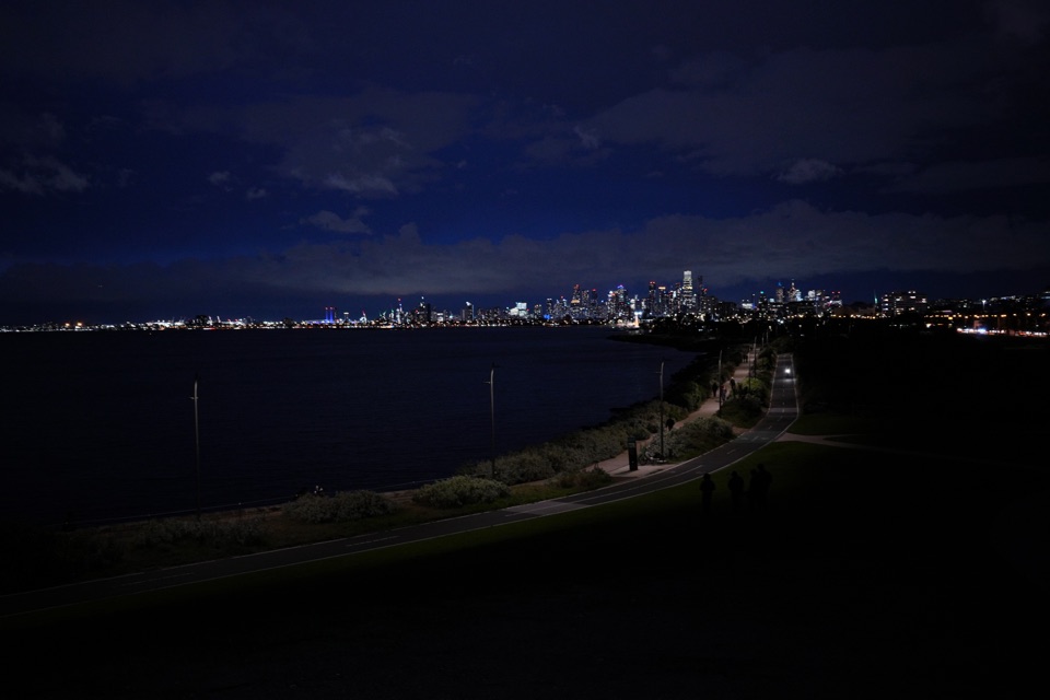 Melbourne skyline glowing across the water at night